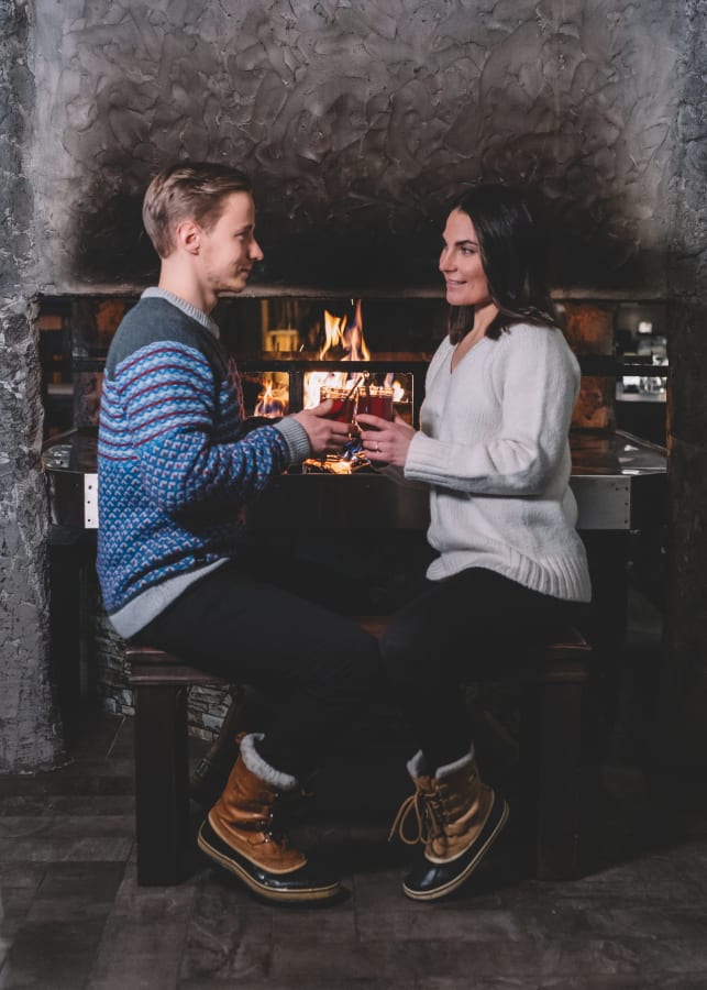 A couple is having a drink by the open fire at the Kota Restaurant.