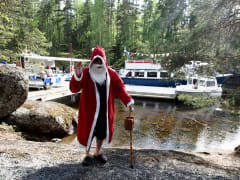 Joulupukki Lapinsalossa vilkuttamassa. Taustalla vene, risteilyalus sekä ihmisiä. Kuva: Janita Juvakka