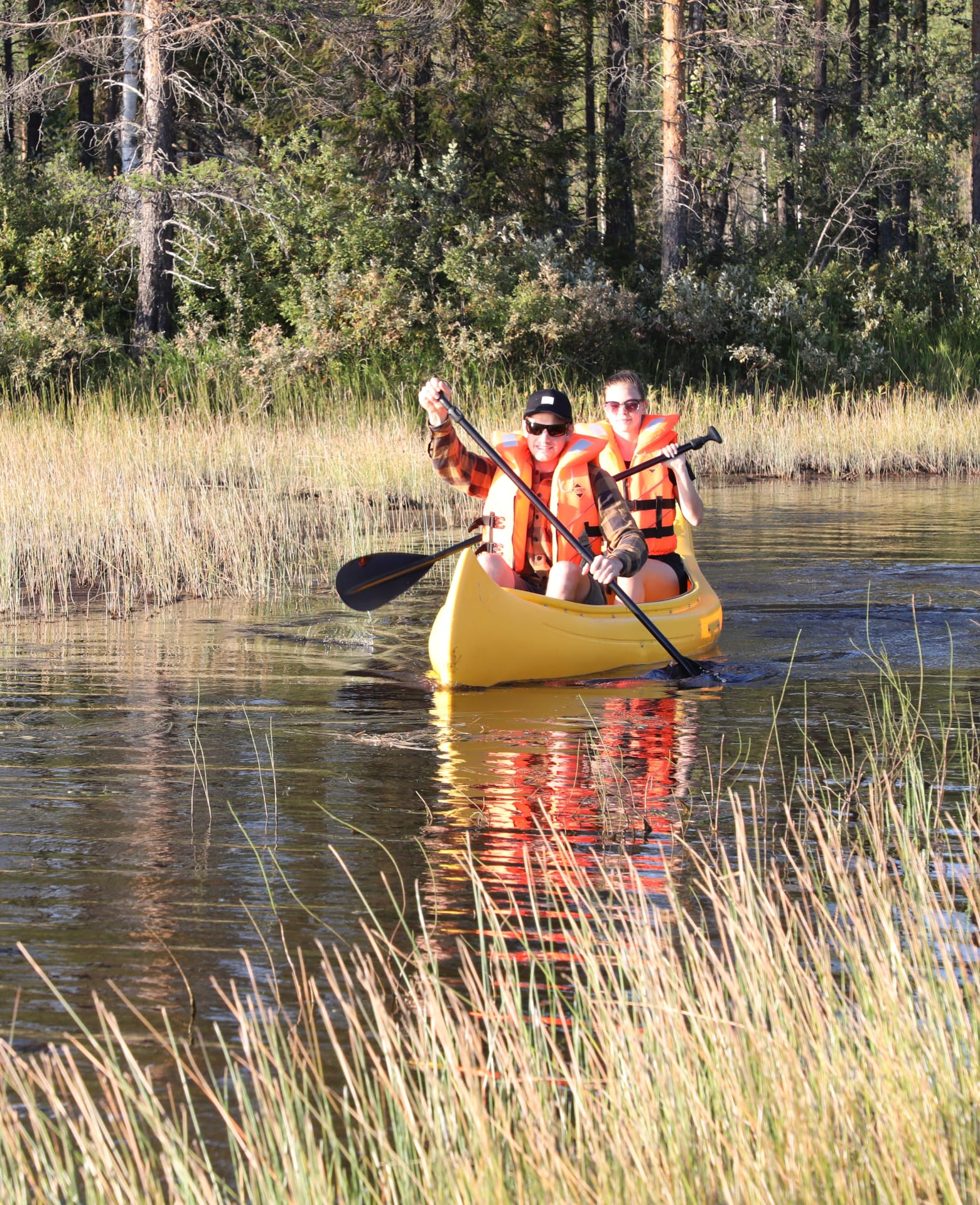 A couple kayaking at Villa Cone Beach on a sunny day, with autumn colors of Ruska decorating the scenery.