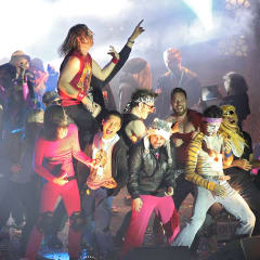 Group of people in colorful clothes playing air guitars