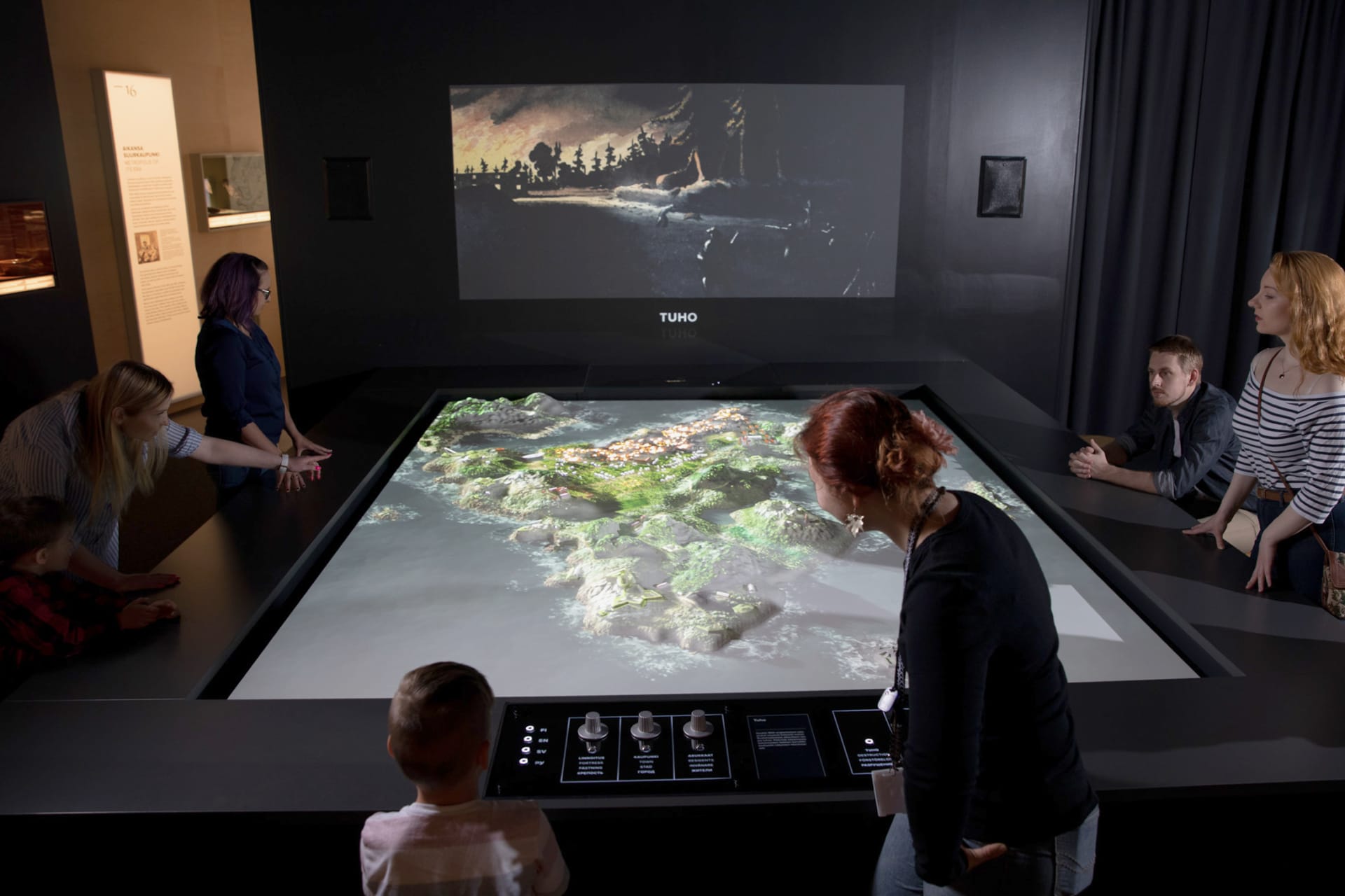 Adults and kids playing with a 3D model of a city map. 