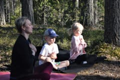 Henkilöitä joogaamassa metsässä