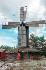 Tuulimyllyn vieressä seisoo henkilö