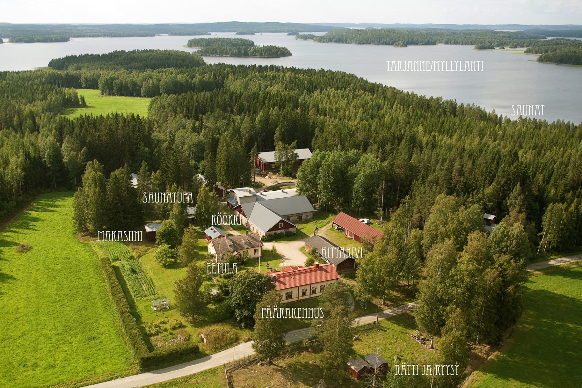 The aerial view of the Ylä-Tuuhonen Farm shows the farm's buildings, fields, forest and Lake Tarjanne.
