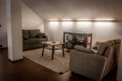 There is a lounge area upstairs with a sofa, a sofa bed, a table and a bookshelf.