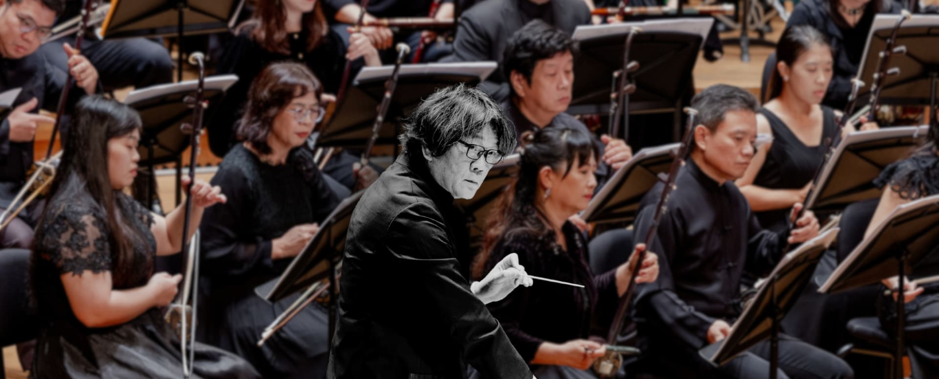 Kaohsiung Traditional Orchestra Taiwan playing on a concert stage, with conductor Kuo superimposed on top of the orchestra in black and white