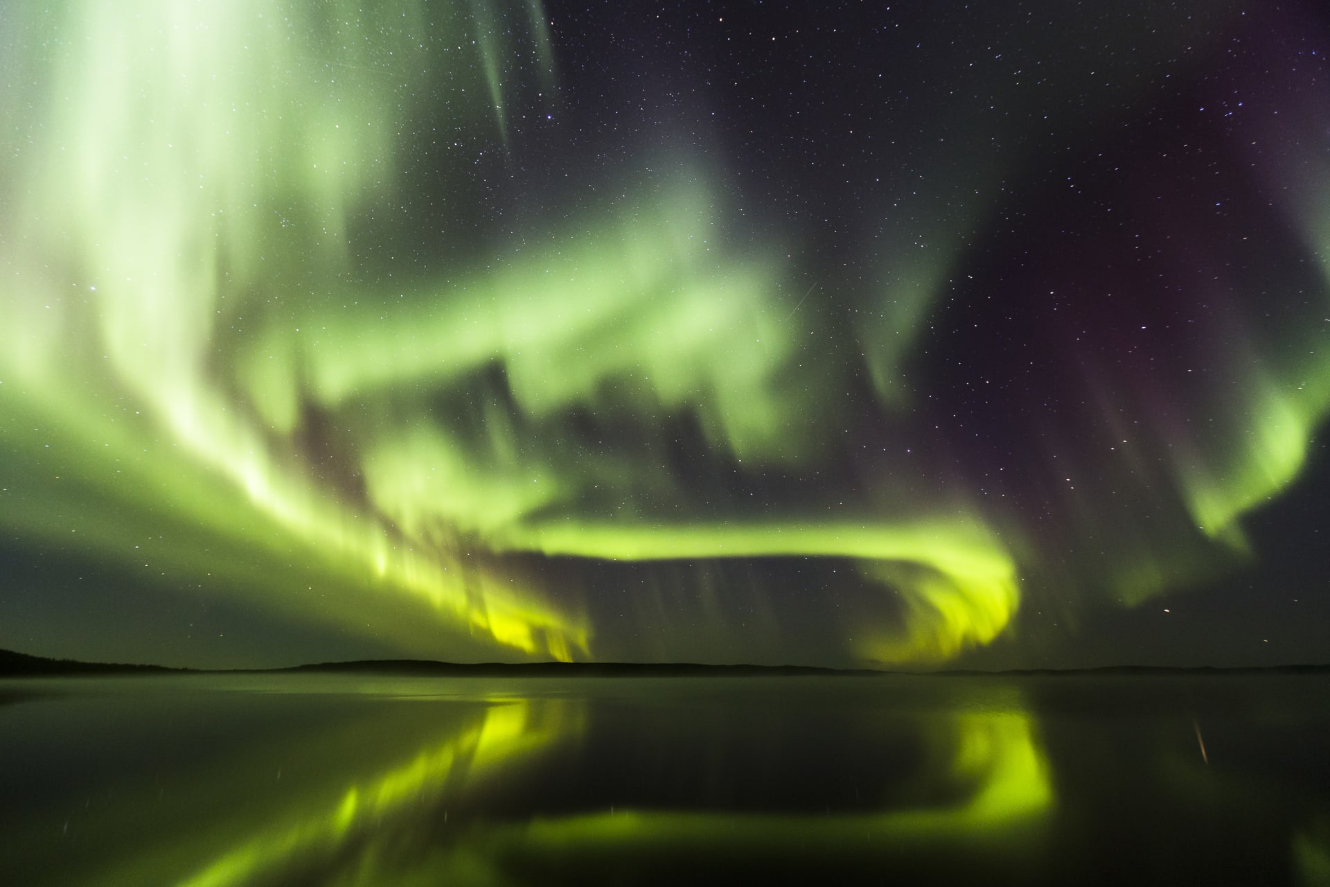 Aurora Borealis dancing in the night sky above frozen lake