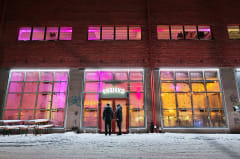The historic Varikko brewery building glowing with purple lights during a Nordic evening