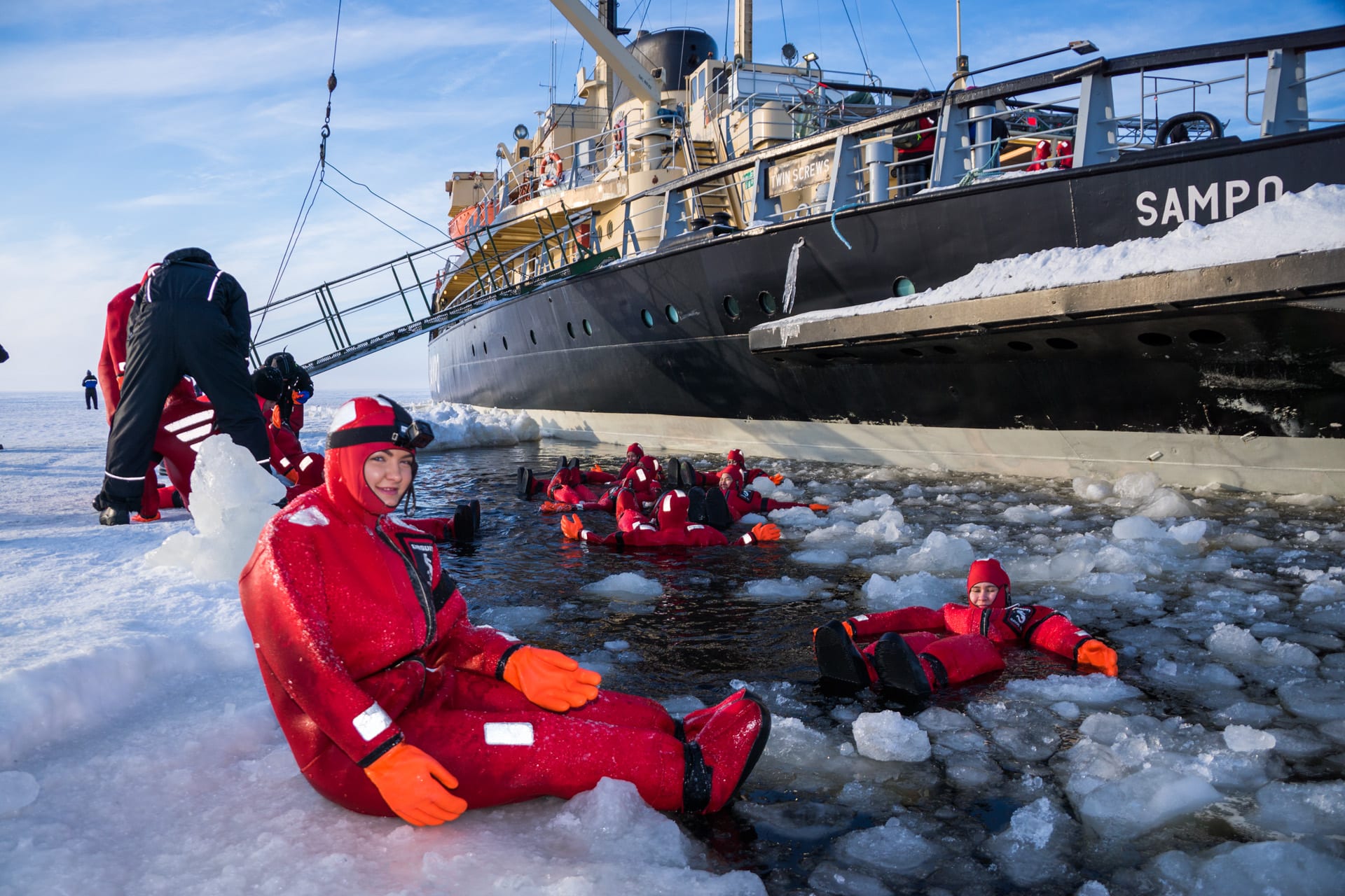 Woman floating in survival suit in the frozen sea by the icebreaker sampo vessel