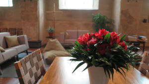 Kuvassa on pöytä jossa on maljakossa punaisia kukkia. 