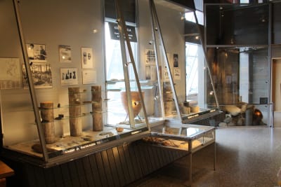 Näyttelyvitriineissä Suomussalmen alueen arkeologisia löytöjä kuten kirveen teriä ja koruja.