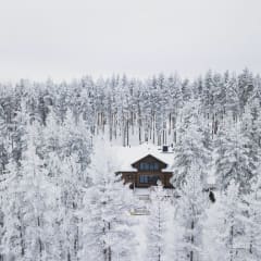 A secluded hideaway surrounded by a beautiful snow-covered pine forest in the heart of Finnish nature.