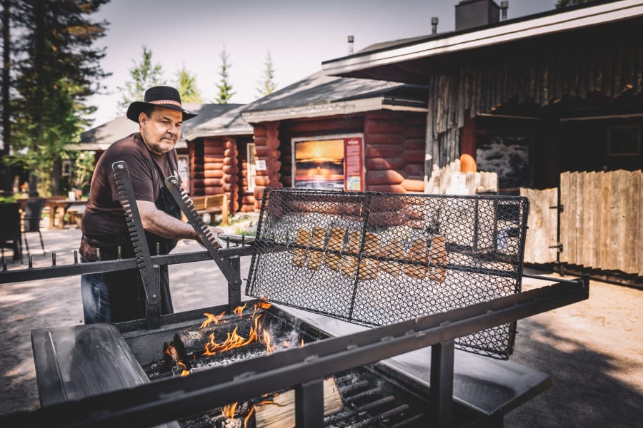 The chef preparing glow fried salmon by the open fire at Santamus Restaurant.