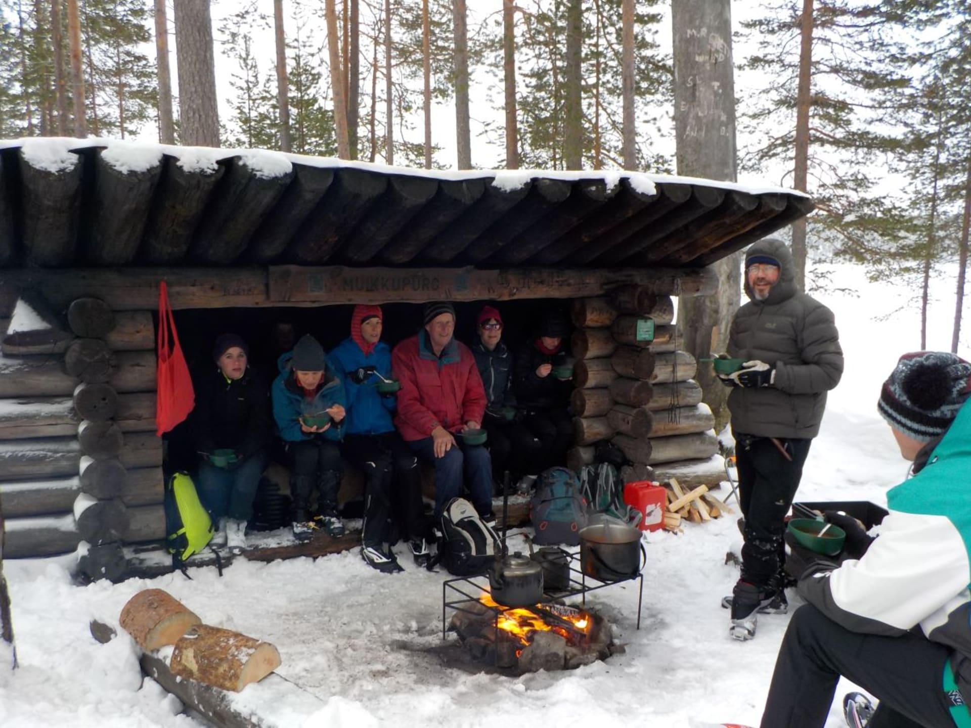 Skiers having lunch around an open fire