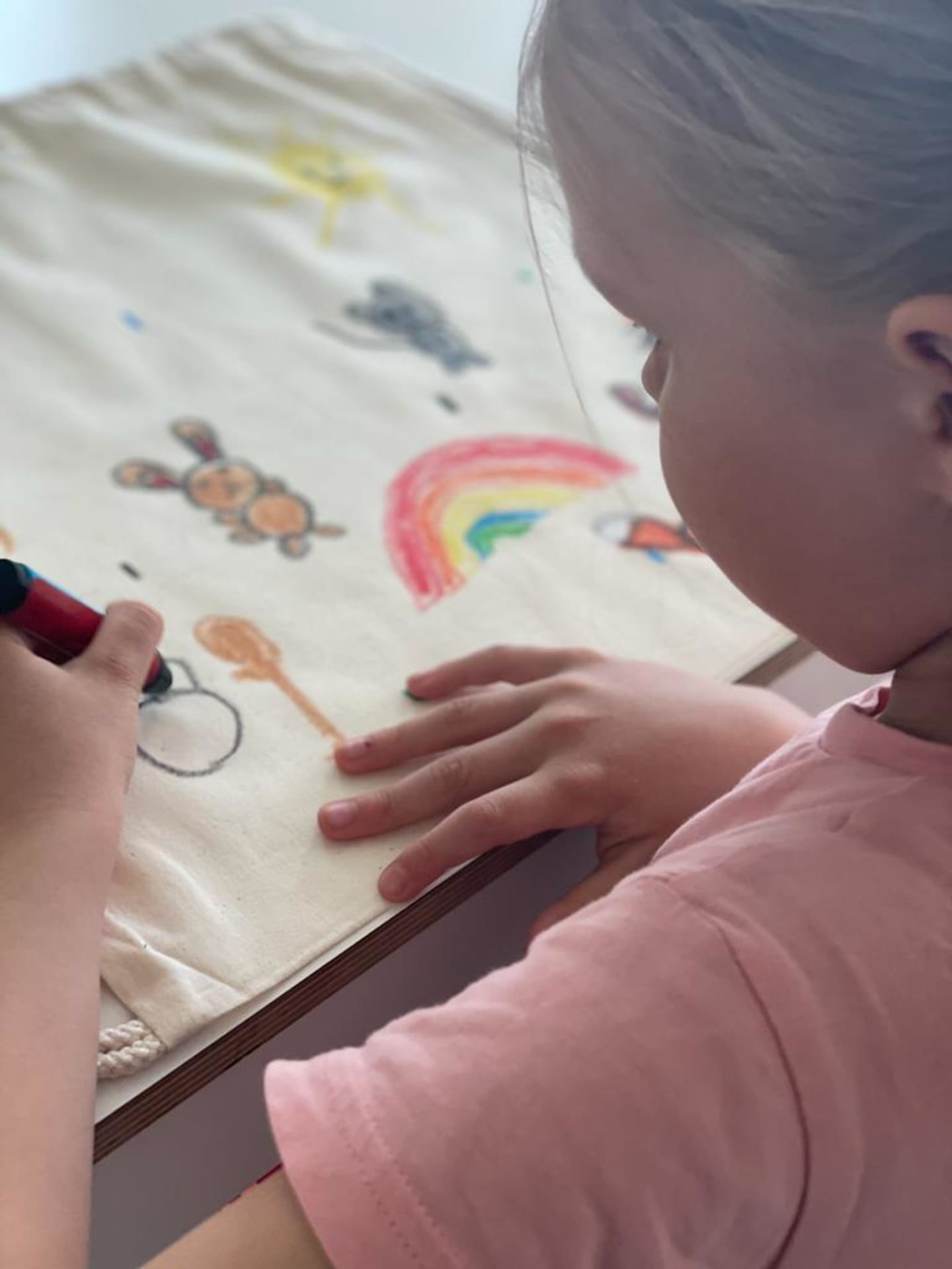 Lapsi piirtää narureppuun kangasliiduilla kesäisen kuvan.