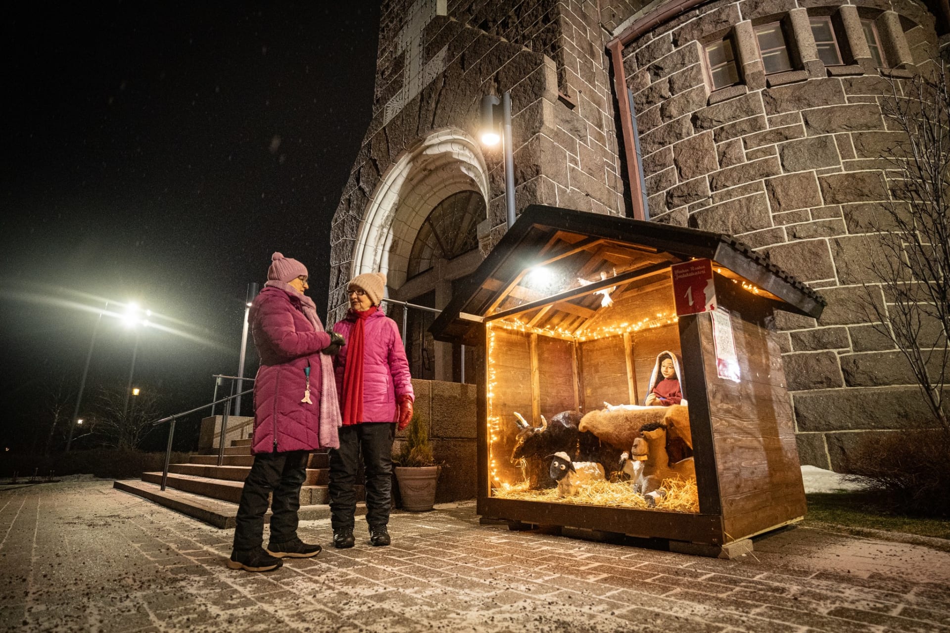 Kaksi henkilöä ihailemassa Wanhan Raahen joulukalenterin luukkua.