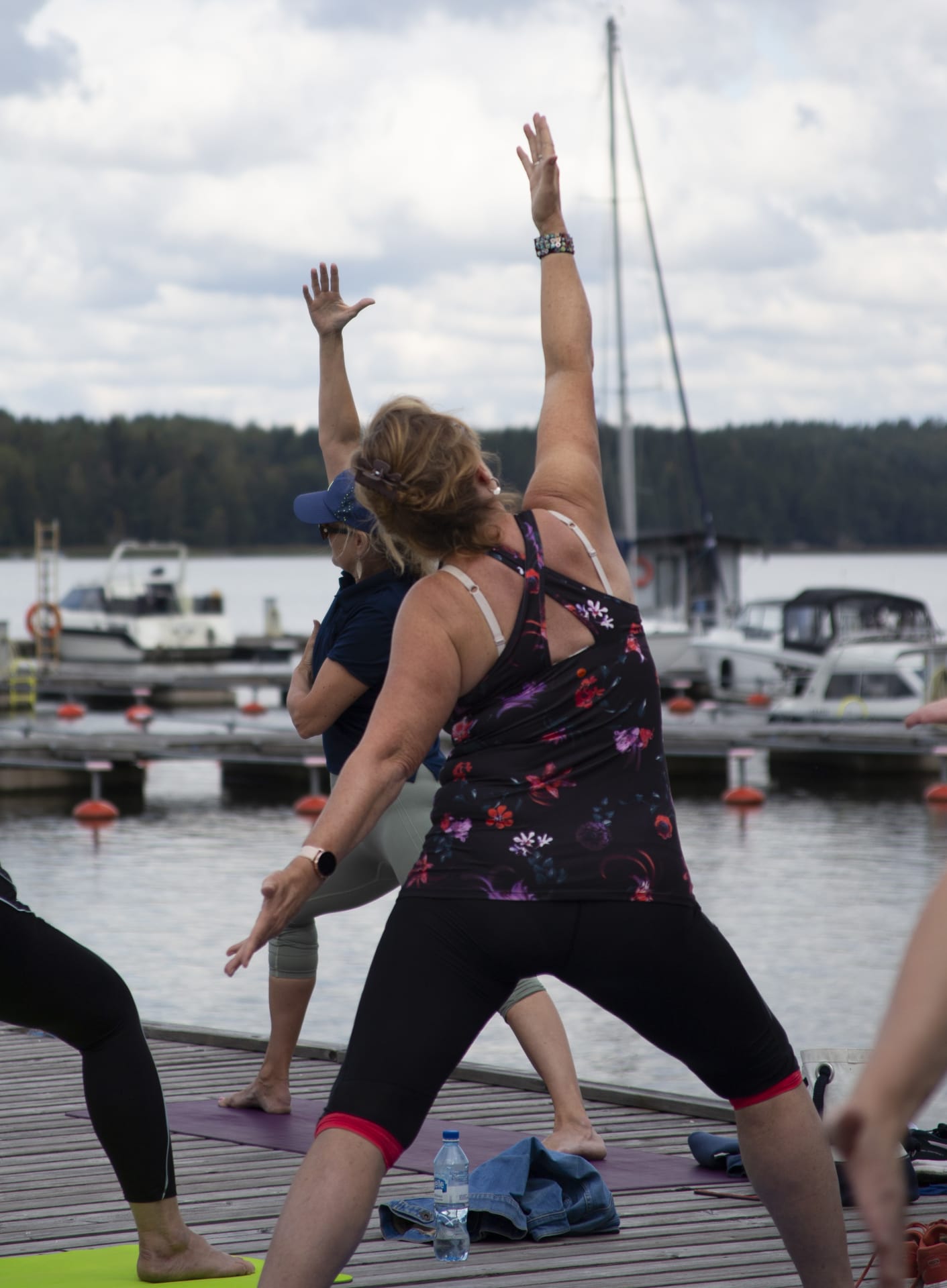 Two ladies exercising yoga on the pier.