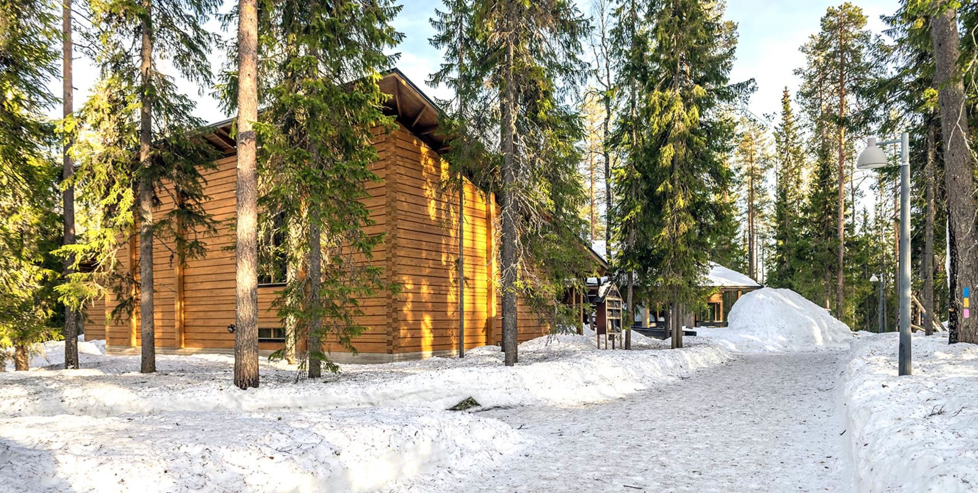 Lumisen metsän keskellä on hirsirakennus. /  In the middle of the snowy forest is a log building. Kuva: Sami Säily.