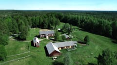 Vanha perinnetila ja useita rakennuksia kuvattuna ilmasta. Ympärillä kansallispuiston metsää.