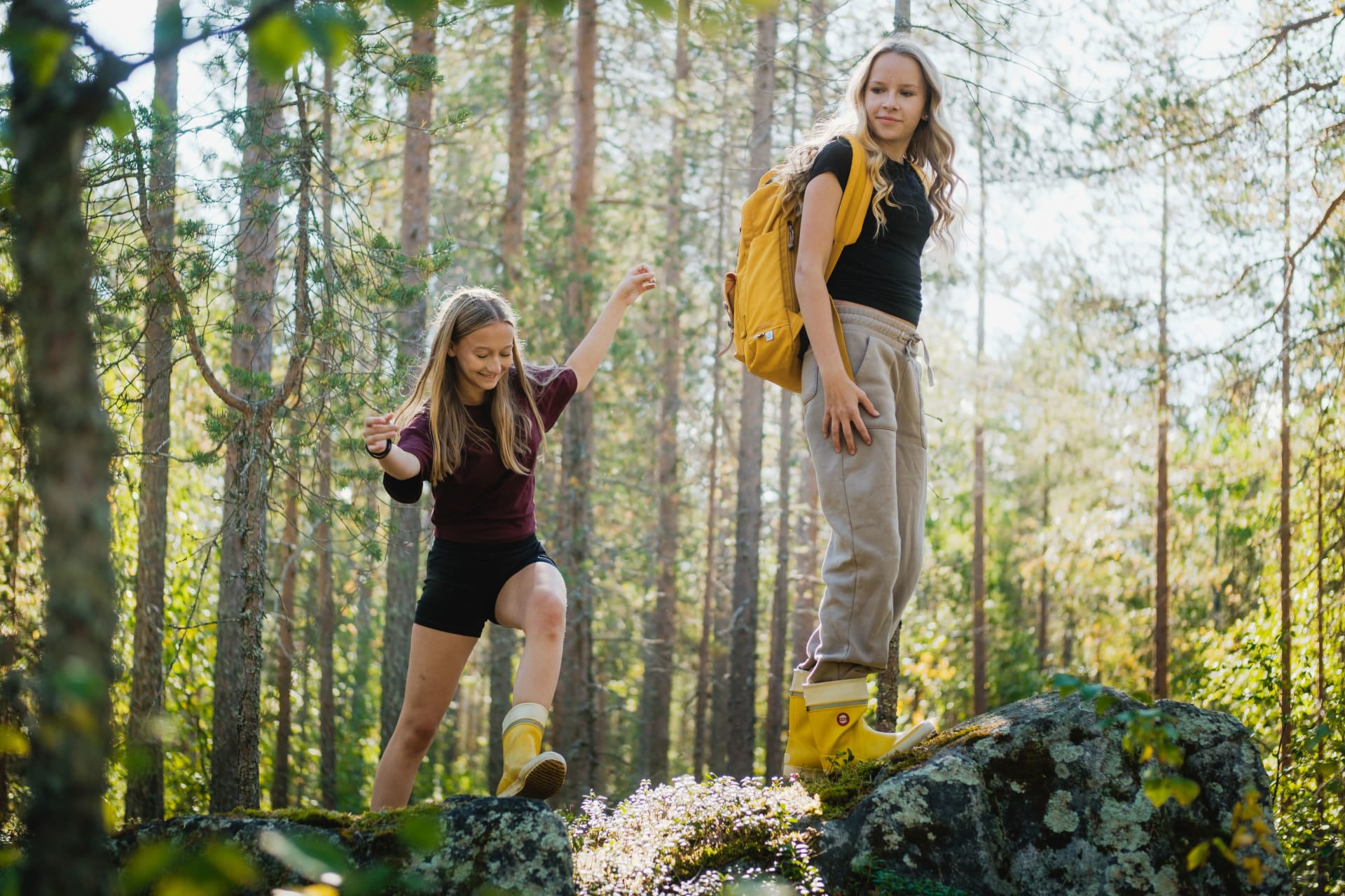 Two adults climbing a rock  in the forest and laughing