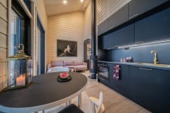 An apartment's living room, with a dining table in the foreground and a pink sofa in the background. A snowy landscape can be seen from the large windows.