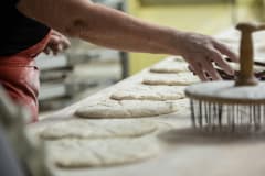 Leivontapöytä, jonka päällä leivotaan vaaleaa leipää.