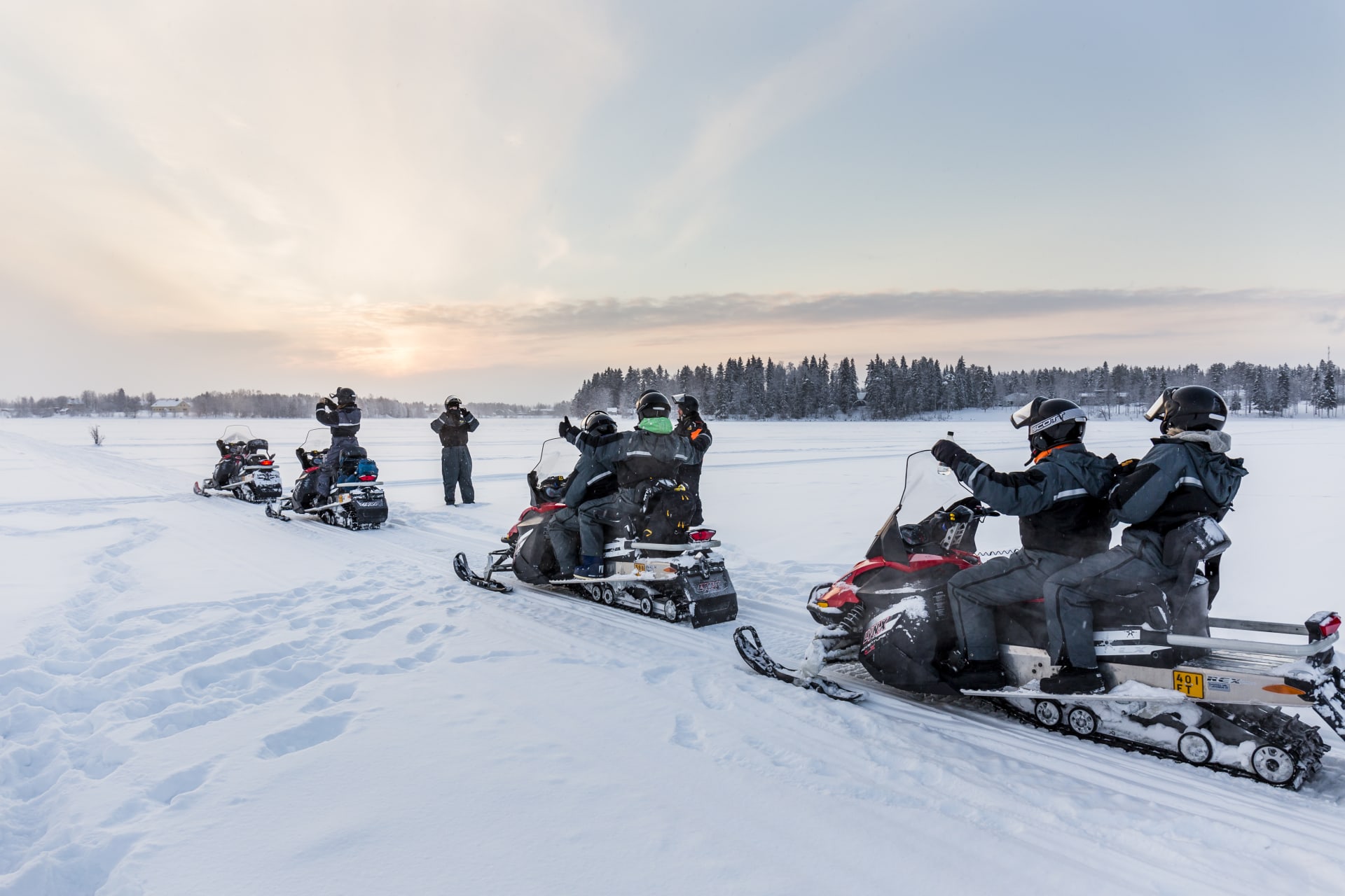 Snowmobiles and guests standing at a Lake