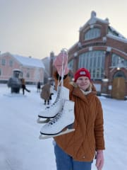 A person holding figure skates outside of the Oulu Market Hall