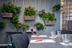 Muistiinpanovälineet kokouspöydällä ja viherkasveja seinustalla