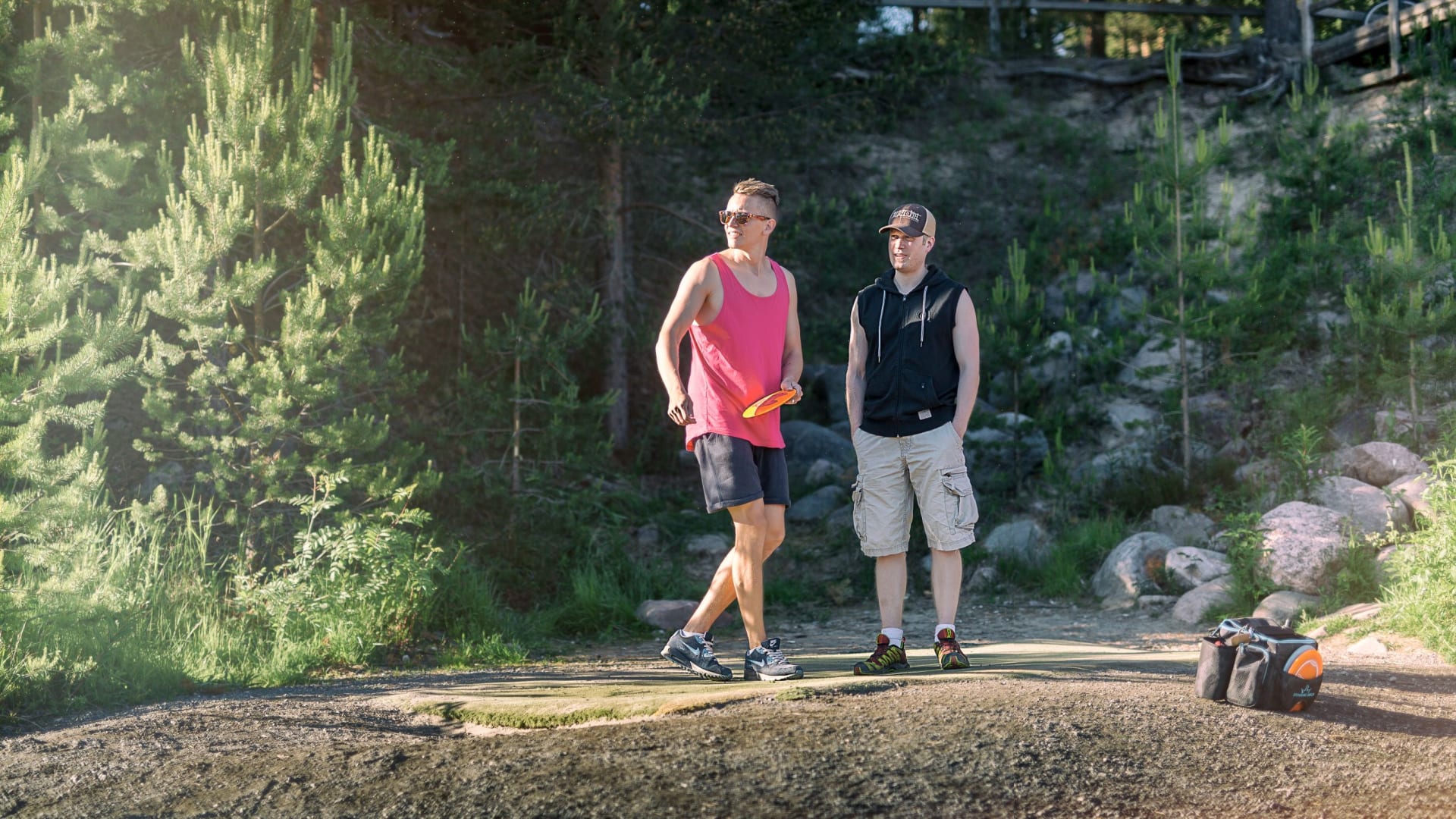 Two men playing Disc Golf in the forest.