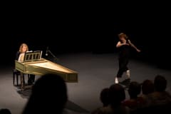 a woman playing harpsichord and another woman dancing