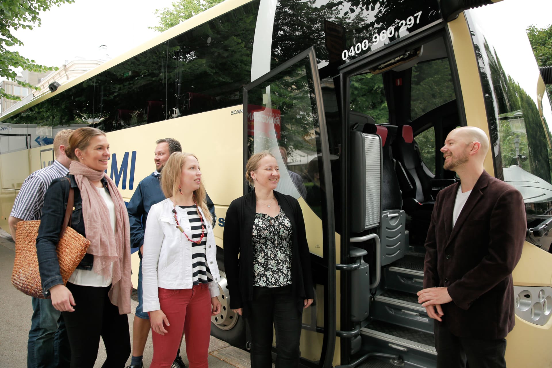 Guide welcoming a group of customers to a tour bus