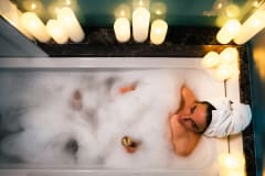 A woman relaxing in a bathtub with bath bubbles and candels