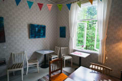 crepe café from inside, room with patterned wallpaper, paintings and old tables and chairs