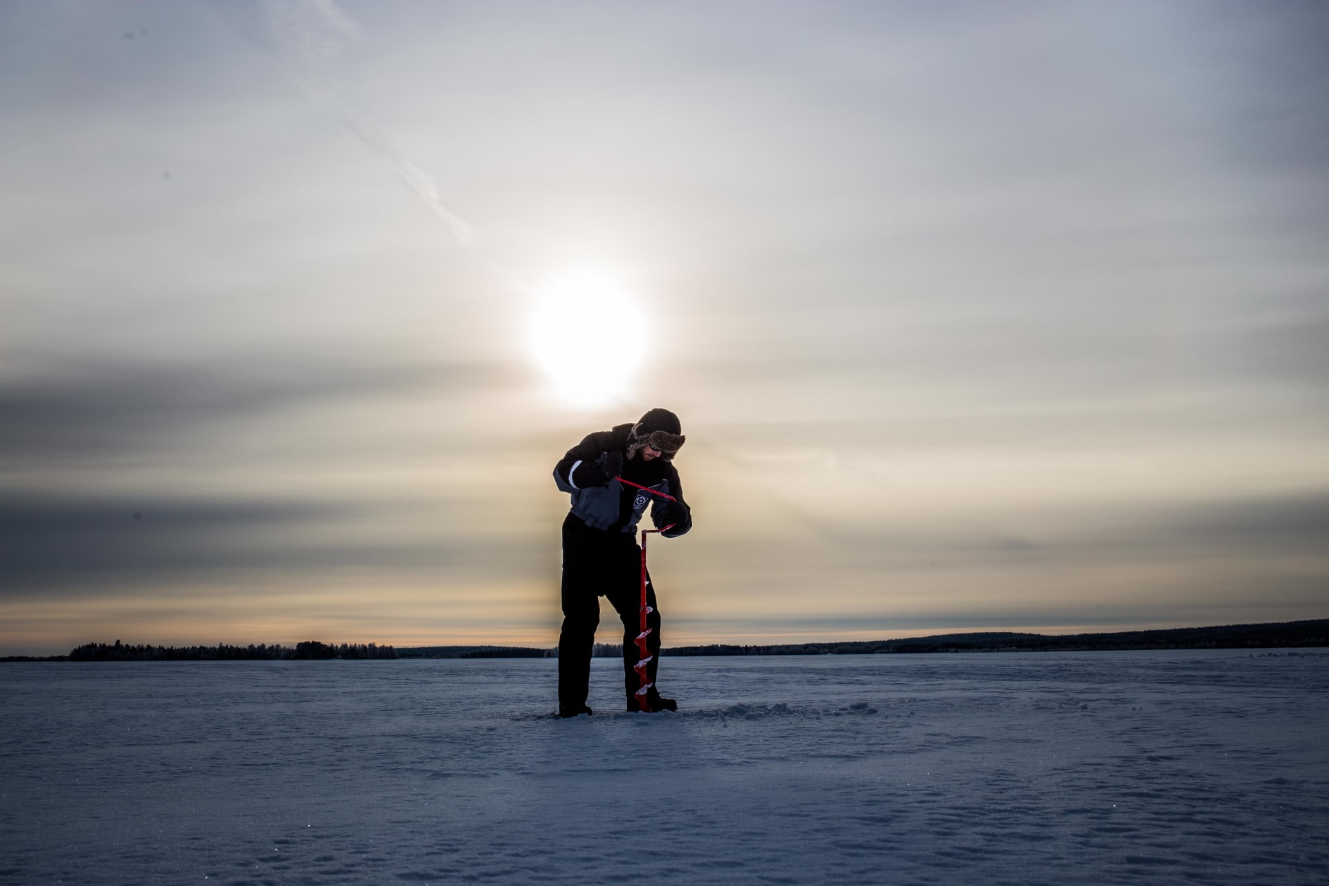 Drilling a hole on ice.