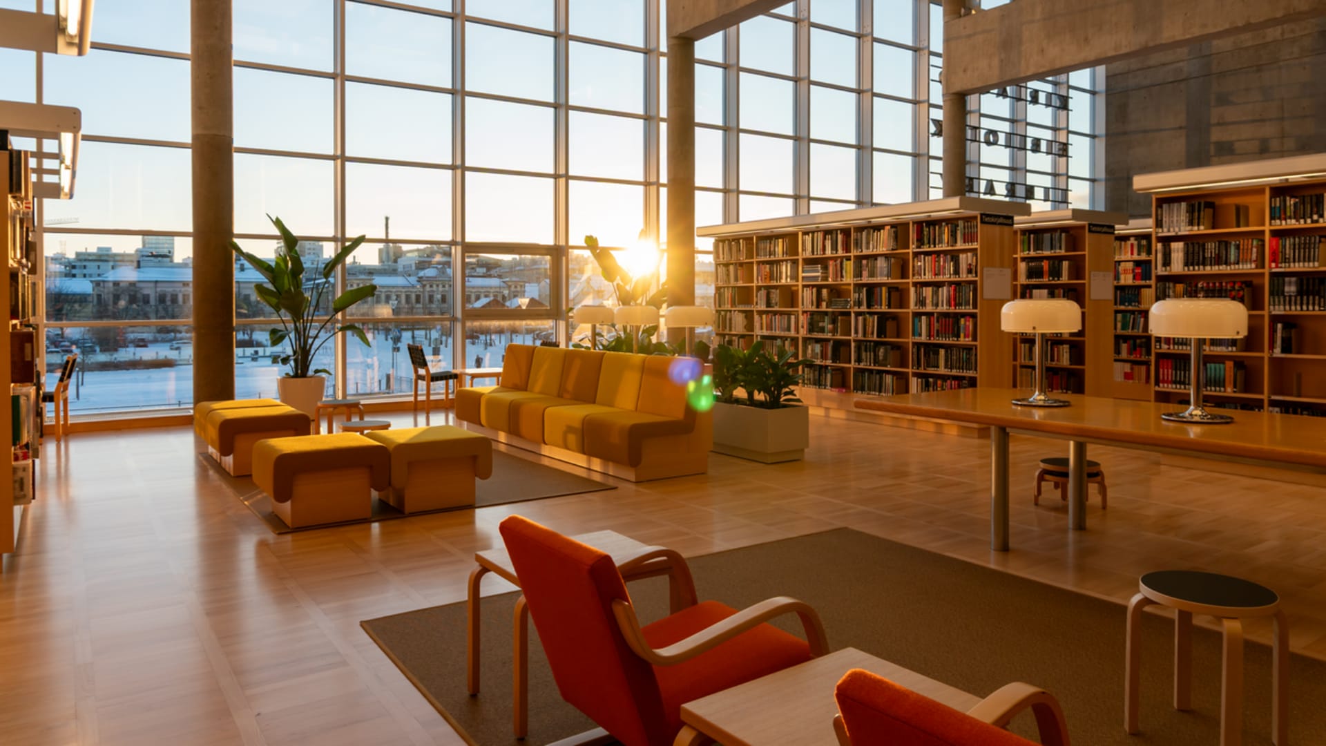 Aulatila, jossa punaisia ja keltaisia istuimia, taustalla kirjahyllyjä.