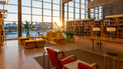 Aulatila, jossa punaisia ja keltaisia istuimia, taustalla kirjahyllyjä.