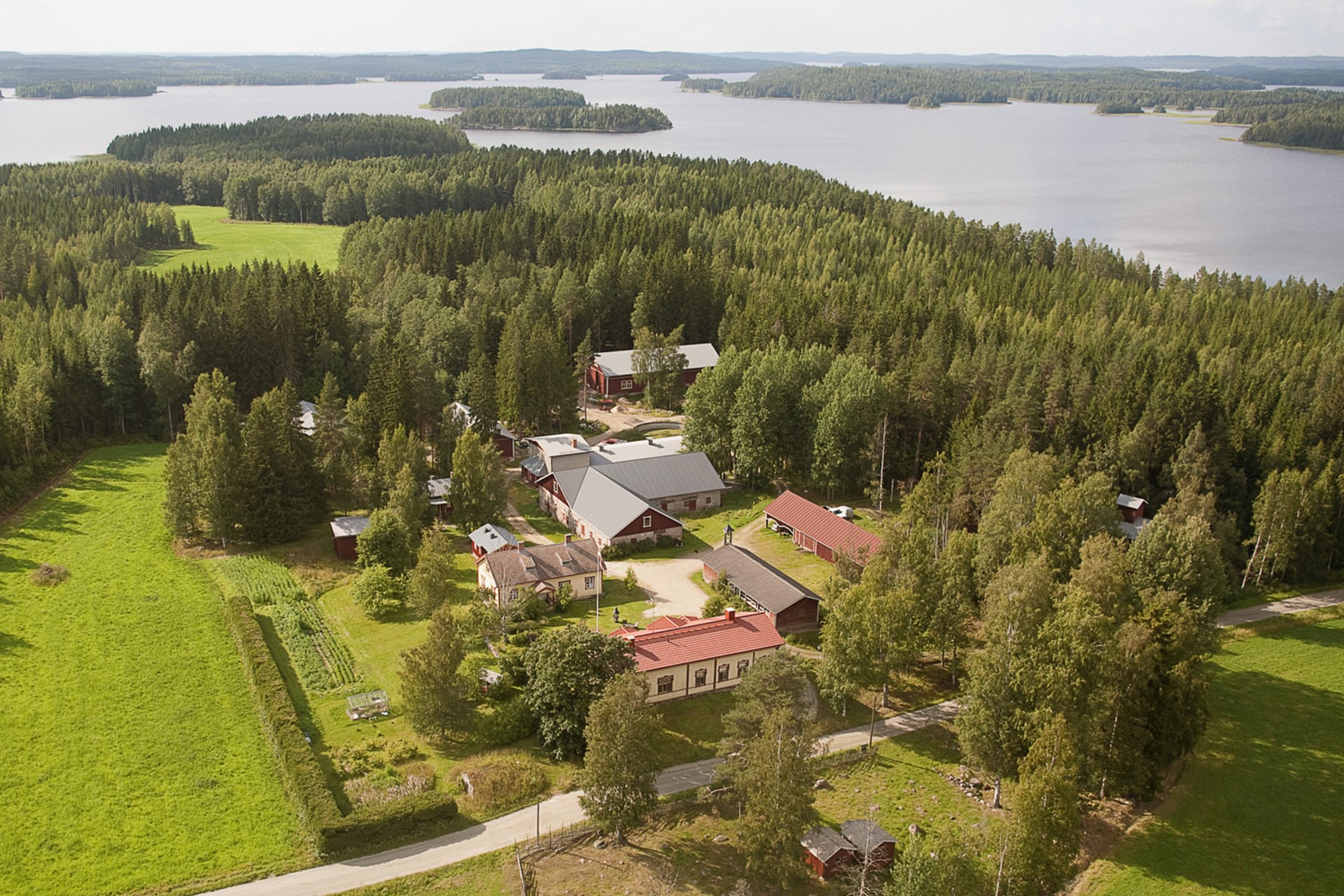 The aerial view of the Ylä-Tuuhonen Farm shows the farm's buildings, fields, forest and Lake Tarjanne.