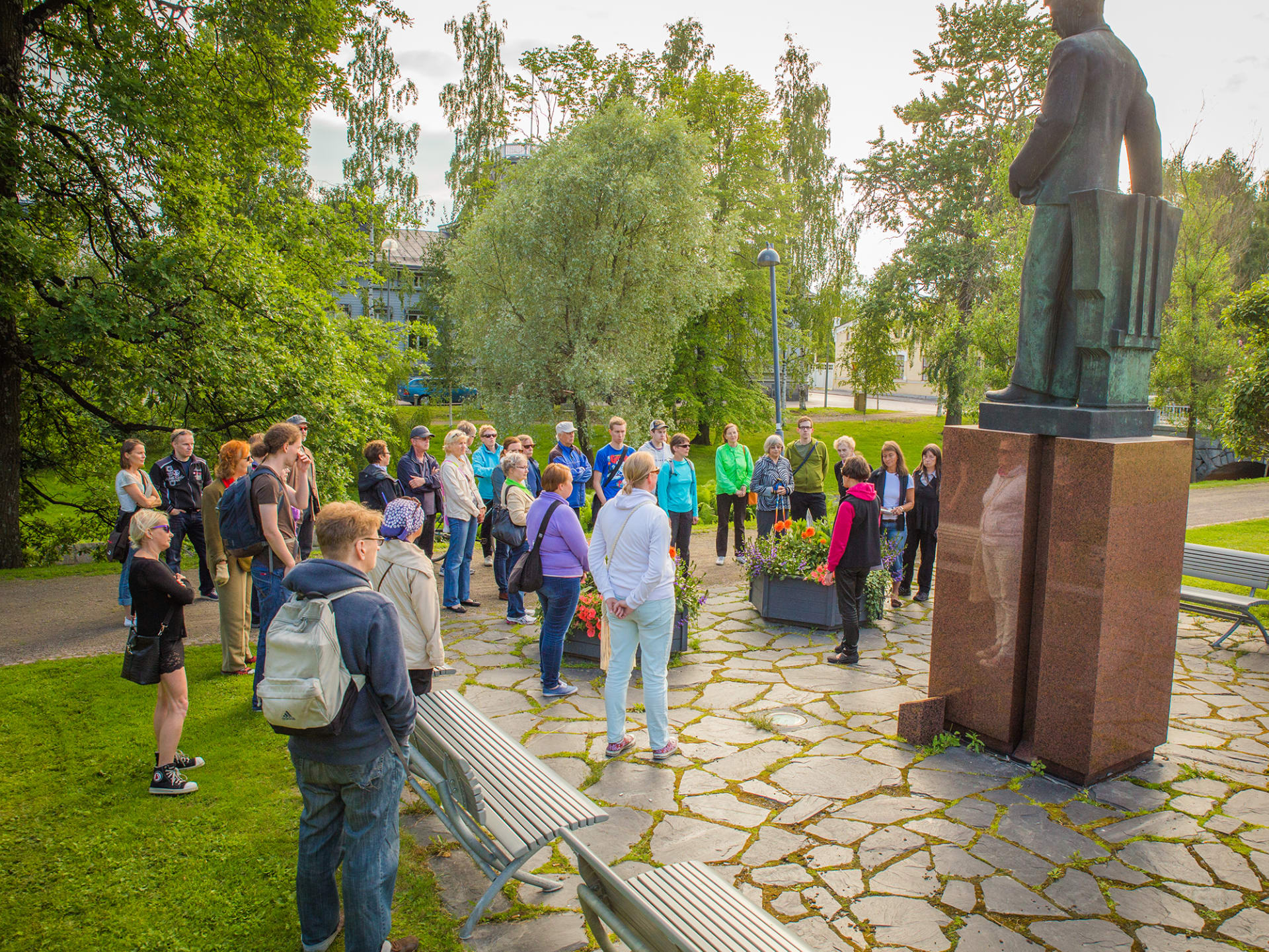 Tour guide with a group of people in front of a statue.