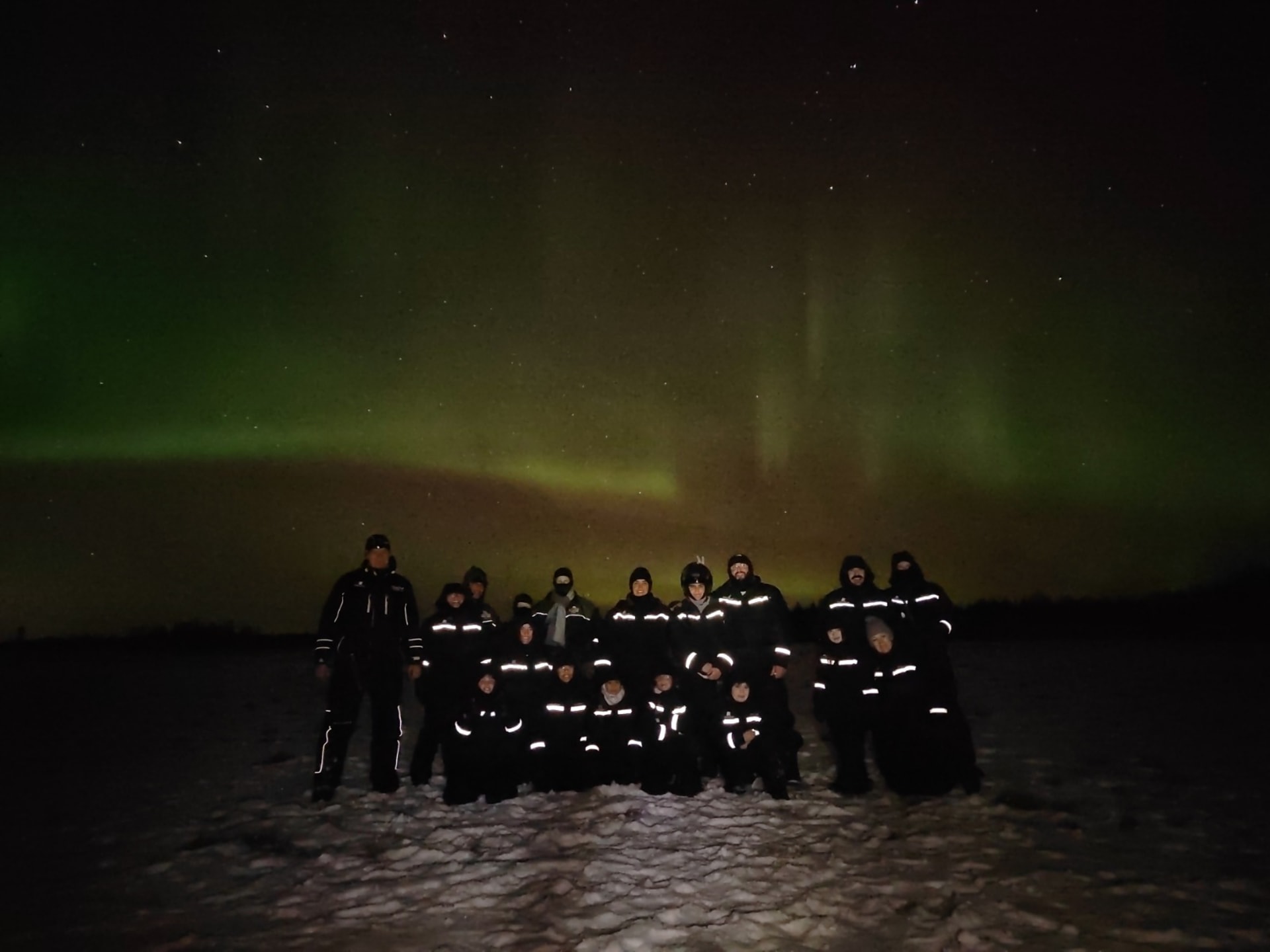 A group picture of the safari in front of Aurora Borealis