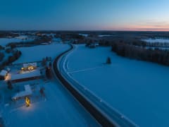 Aerial view of the winding Taikayöntie Road in a snowy landscape in winter.