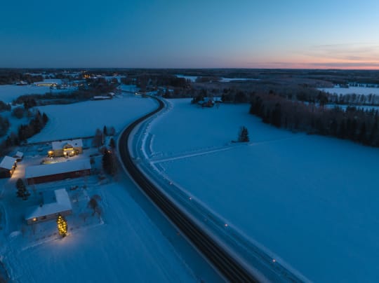 Aerial view of the winding Taikayöntie Road in a snowy landscape in winter.