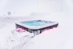 Snow covered stairs and the hot tub in a winter environment.