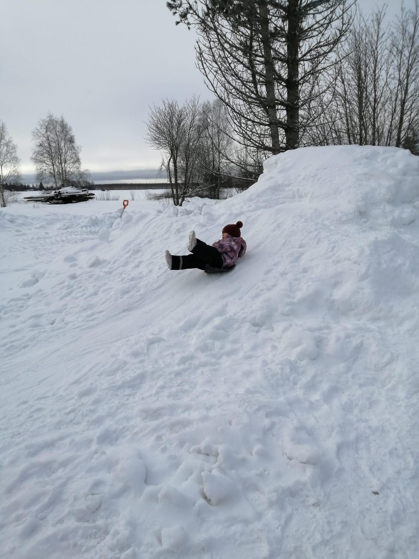 Lapsi laskee lumista liukumäkeä