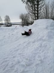 Lapsi laskee lumista liukumäkeä