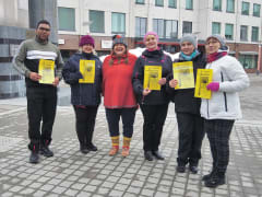 Good Will Elf smiling with customers holding certificates at the Lordi's Square.