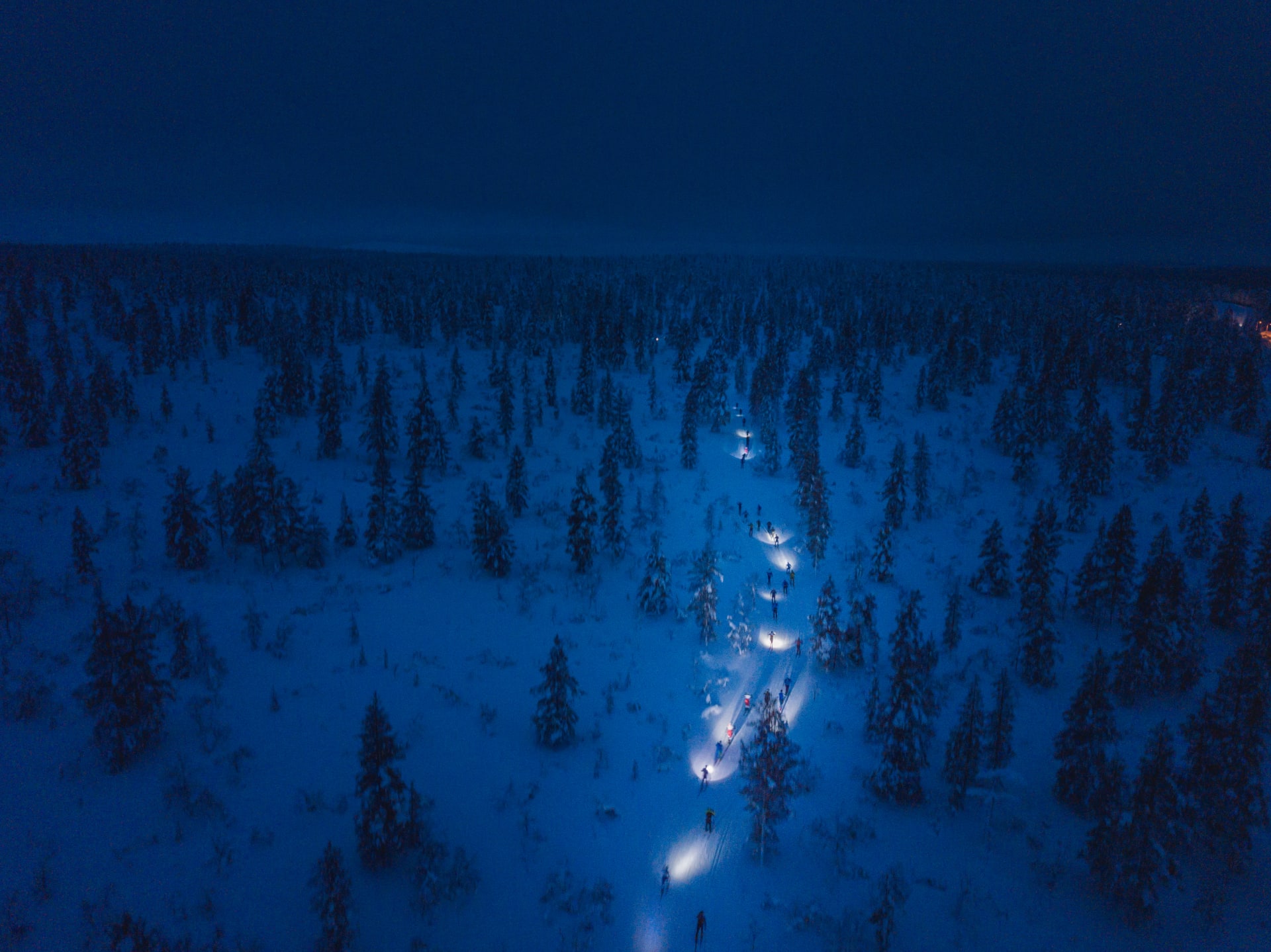 Ilmakuva Kiilopäähiihdosta otsalamppujen valossa hiihtävistä kilpailijoista. 
