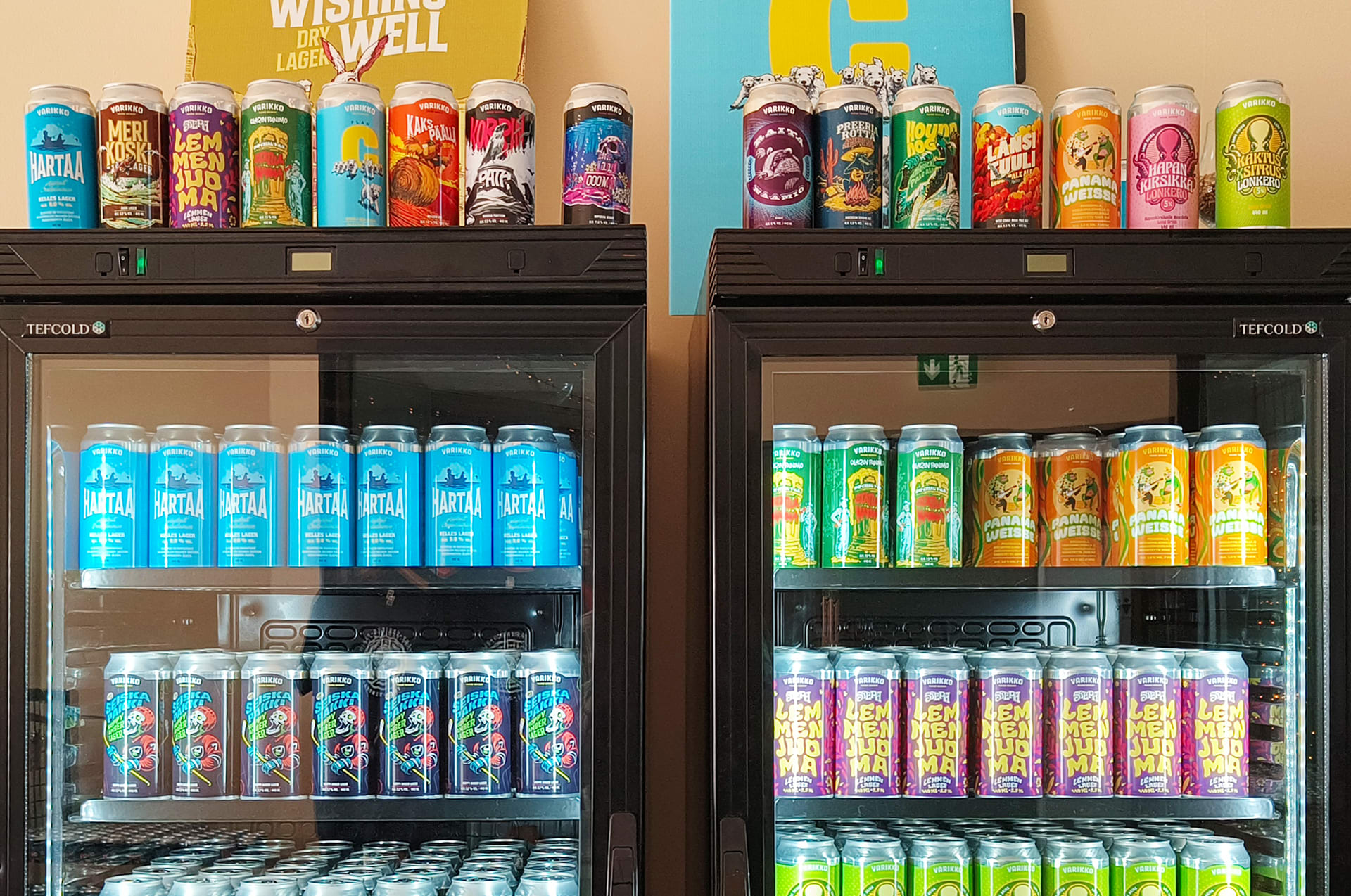A well-stocked display fridge with colorful house-made lonkero and soda cans at Varikko