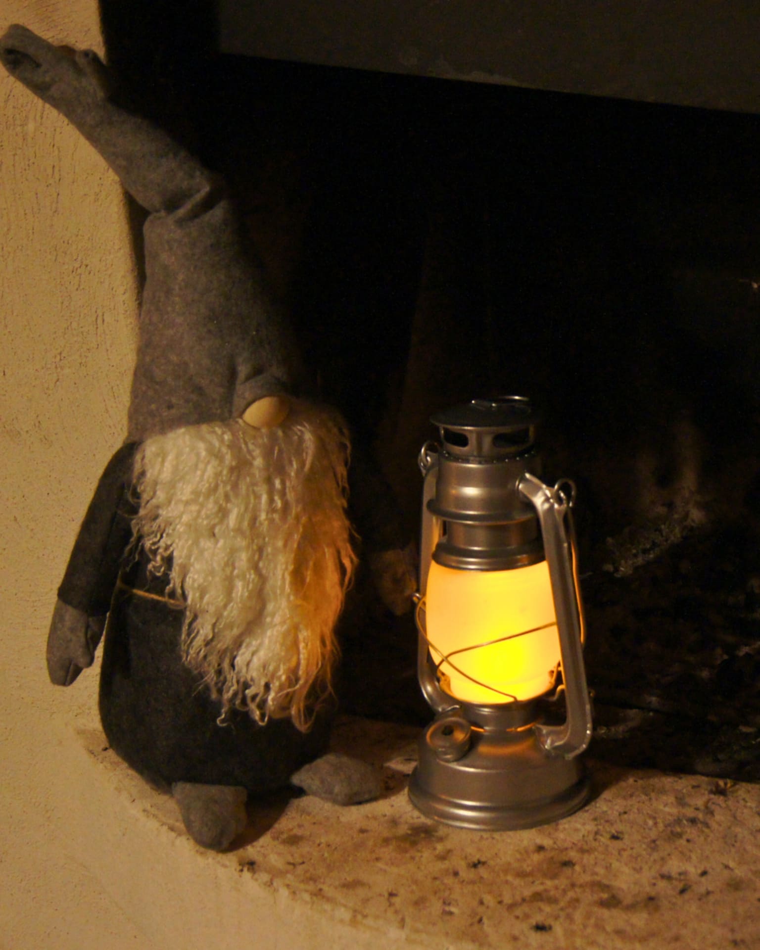 A Christmas elf decoration and lantern by a fireplace