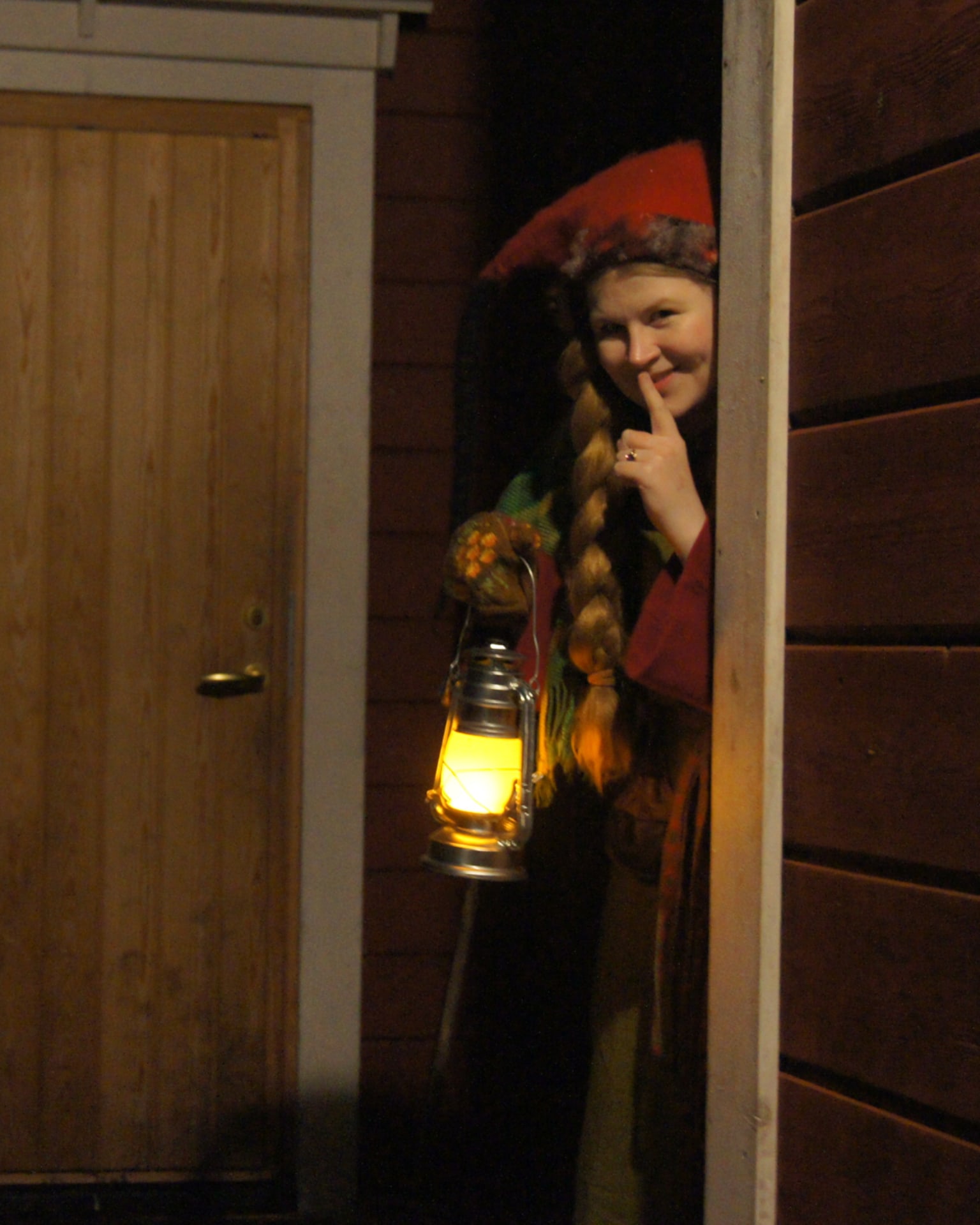 A tonttu (home elf) peeking out from behind a house